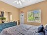 Bedroom featuring a ceiling fan with integrated lighting and a large window with horizontal blinds