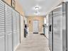 Kitchen featuring white cabinetry, stainless steel appliances, dual ceiling-mounted lighting, and tile flooring with louvered closet doors