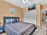 Room featuring four-panel louvered closet doors, neutral wall finish, and white ceiling fan with integrated lighting