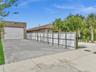 Exterior featuring a detached garage with roll-up door, paved permeable driveway, and full-height privacy fencing