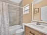Bathroom featuring a vanity with a light wood finish, white countertop, integrated rectangular sink, and matte black hardware, accompanied by a tub en
