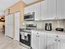 Kitchen featuring white shaker-style cabinetry, stone-finish countertops, stainless steel appliances, and wood-finish flooring
