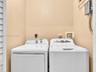 Laundry area featuring side-by-side white washer and dryer, recessed wall-mounted utility connections, and louvered door access