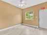 Interior room featuring neutral-toned walls, tile flooring with a stone-finish pattern, a white ceiling fan with integrated lighting, and a single-pan