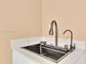 Drop-in stainless steel sink featuring an integrated ledge, high-arc pull-down faucet, auxiliary filtered water tap, and stone-composite countertop wi