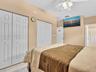 Room featuring two sets of white six-panel closet doors, ceiling fan with integrated lighting, and neutral-toned wall paint