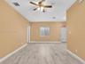 Interior space featuring wood-finish tile flooring, a neutral wall palette, a multi-blade ceiling fan with integrated lighting, and a single sliding w