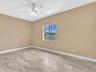 Room featuring neutral-toned walls, wood-finish tile flooring, a white ceiling fan with integrated lighting, and a window with a horizontal sliding pa