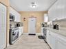 Kitchen featuring white shaker-style cabinetry, stone-finish countertops, stainless steel appliances, and tile flooring
