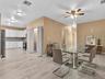 Open-concept interior featuring light tile flooring, white cabinetry, louvered closet doors, and a ceiling fan