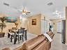 Open-concept living space with tile flooring, ceiling fan, and louvered double-door storage closet