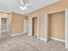 Room featuring wood-finish tile flooring, dual bi-fold closets, a central ceiling fan with integrated lighting, and white six-panel interior doors