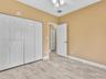 Interior room featuring stone-finish tile flooring, multi-panel closet doors, six-panel interior doors, and a ceiling-mounted light fixture