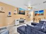 Neutral wall tones, wood-finish flooring, ceiling fan with integrated lighting, and white cabinetry featuring an electric fireplace insert