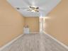 Room featuring wood-finish tile flooring, white built-in cabinetry with a countertop sink, and a ceiling-mounted light fixture with a fan