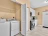 Utility space featuring white cabinetry, wood-finish tile flooring, louvered closet doors, and wire shelving