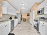 Kitchen featuring white shaker-style cabinetry, stone-finish countertops, stainless steel appliances, and tile flooring