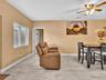 Neutral-toned interior space featuring light-colored stone-finish flooring, a multi-blade ceiling fan with integrated lighting, and a white-framed win
