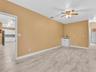Interior space featuring wood-finish tile flooring, ceiling fan with integrated lighting, and a built-in wet bar with white cabinetry and a dark fauce