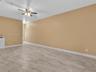 Spacious interior featuring wood-finish tile flooring, ceiling fan with integrated lighting, and a built-in cabinetry unit with countertop