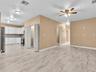 Kitchen featuring white cabinetry, stone-finish countertops, and stainless steel appliances, complemented by wood-finish flooring and a ceiling fan