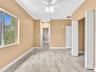 Room featuring wood-finish flooring, a multi-blade ceiling fan with integrated lighting, a sliding closet door, and dual interior doors