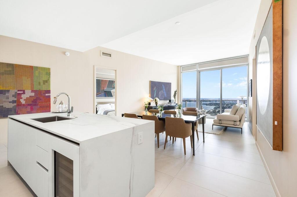 Center island featuring a white stone countertop, undermount sink, and integrated wine refrigeration, complemented by large-format tile flooring and f