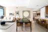 Open-concept interior featuring large-format tile flooring, floor-to-ceiling windows, and a kitchen island with wood-veneer cabinetry and a solid-surf