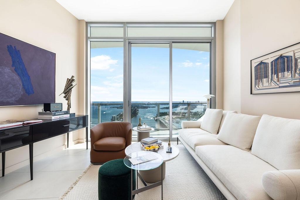 Floor-to-ceiling windows with sliding door access to a balcony, complemented by neutral tile flooring