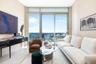Floor-to-ceiling windows with sliding door access to a balcony, complemented by neutral tile flooring