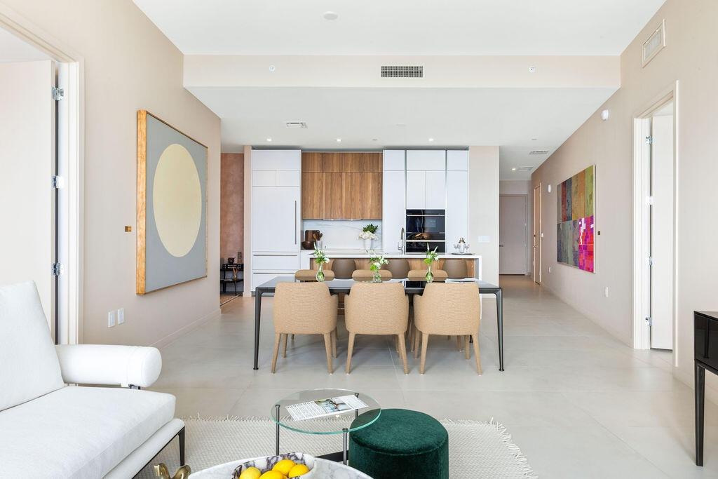 Open-concept kitchen featuring custom wood-finish and matte white cabinetry, integrated appliances, and a central island with a stone-finish counterto