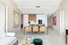 Open-concept kitchen featuring custom wood-finish and matte white cabinetry, integrated appliances, and a central island with a stone-finish counterto