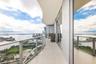 Curved balcony featuring tile flooring, full-height glass sliding doors, and a metal railing with glass panels