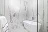 Freestanding soaking tub featuring a wall-mounted faucet, floor-to-ceiling large-format stone-finish tile surround, handheld shower fixture, and glass