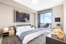 Full-height sliding glass doors with access to a private balcony, neutral wall finishes, and overhead recessed lighting