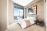 Floor-to-ceiling glass sliding door, large private balcony, textured stone feature wall, and neutral polished flooring