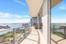 Expansive covered balcony featuring glass railings, large-format tile flooring, and floor-to-ceiling glass doors