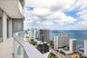 Curved exterior balcony with glass railing, large-format tile flooring, and expansive floor-to-ceiling windows