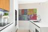 Kitchen featuring minimalist white cabinetry, wood-finish upper cabinets, integrated wall oven, white stone-surface countertops, and a stainless steel