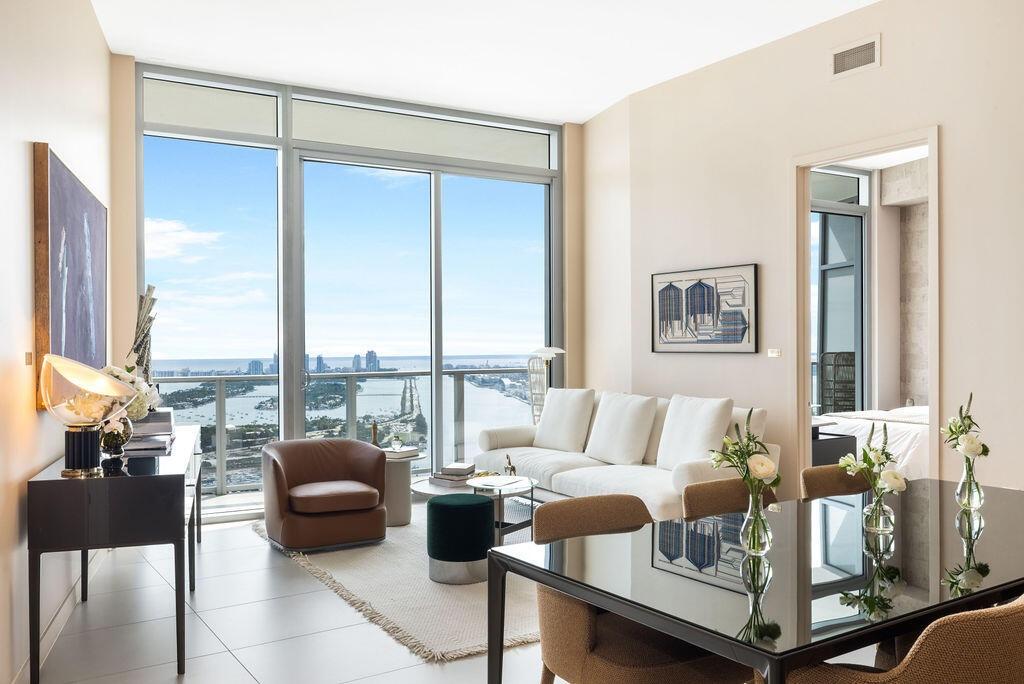 Floor-to-ceiling windows featuring panoramic water and city skyline outlooks, large-format tile flooring, and glass balcony railings