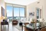 Floor-to-ceiling windows featuring panoramic water and city skyline outlooks, large-format tile flooring, and glass balcony railings