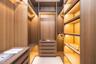 Custom walk-in closet featuring floor-to-ceiling wood-finish cabinetry, integrated linear task lighting, built-in drawer units, and open shelving