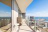 Curved balcony featuring large-format tile flooring and a glass-paneled railing system with a metal frame