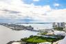 High-altitude perspective featuring expansive water frontage, bridge infrastructure, urban skyline, and a large manicured green space