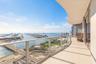 Curved, expansive balcony featuring large-format tile flooring and a glass panel railing