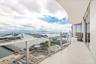 Curved wrap-around balcony featuring expansive tile flooring and a glass panel railing
