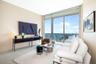 Floor-to-ceiling windows, sliding glass door, private balcony, neutral large-format tile flooring, and water backdrop