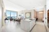 Open-concept interior featuring an oversized waterfall-edge stone island, floor-to-ceiling glass windows, high ceilings with recessed lighting, and ex