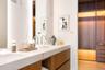 Floating vanity with dual rectangular undermount sinks, stone-finish countertops, integrated LED mirror lighting, and custom wood-finish cabinetry inc