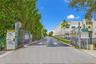 Paved entrance driveway featuring chain-link fencing, dual-gate access, and concrete-surfaced approach